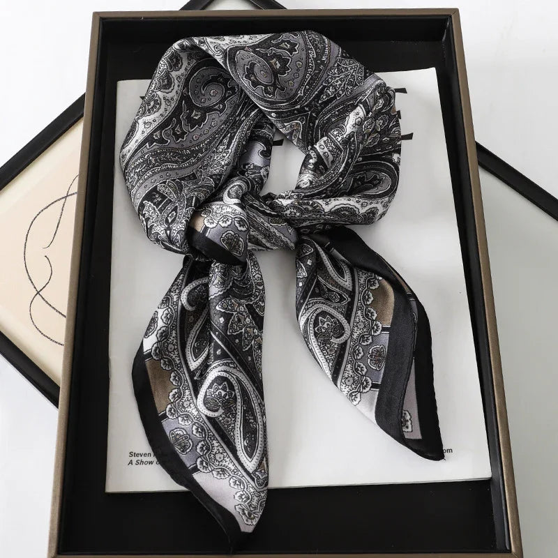 Black and gray paisley silk scarf with intricate patterns, displayed in a framed box with artwork underneath