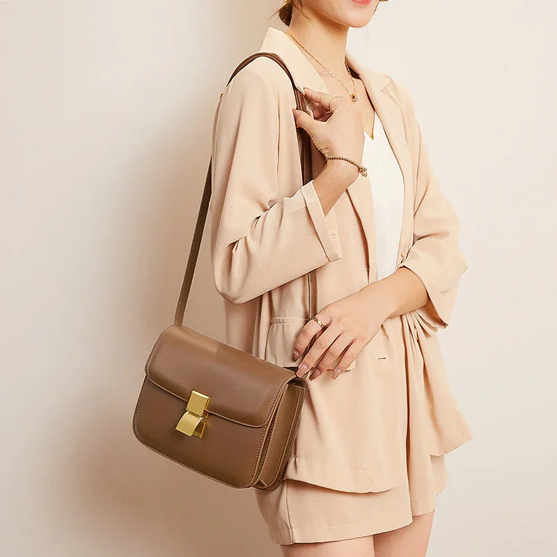 Woman wearing beige blazer and shorts with a brown leather crossbody bag featuring gold clasp