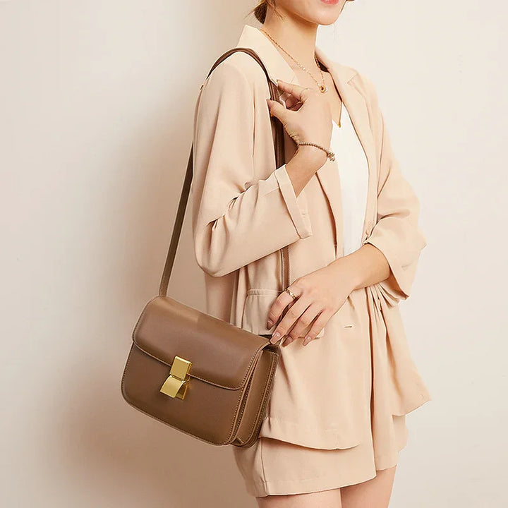 Woman wearing beige blazer and shorts with a brown leather crossbody bag featuring gold clasp