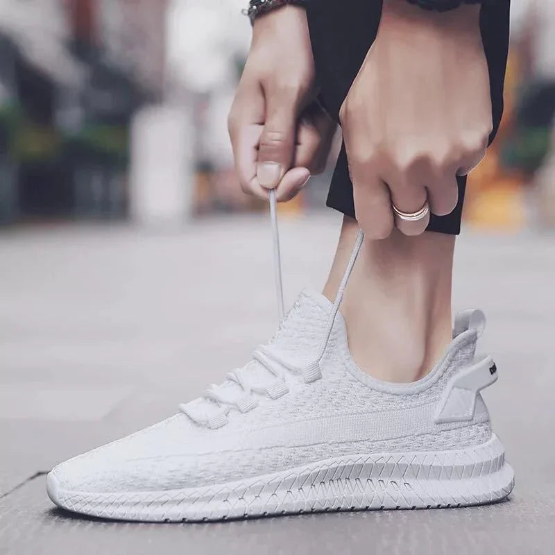Close-up of hands tying white knitted running shoes on urban sidewalk