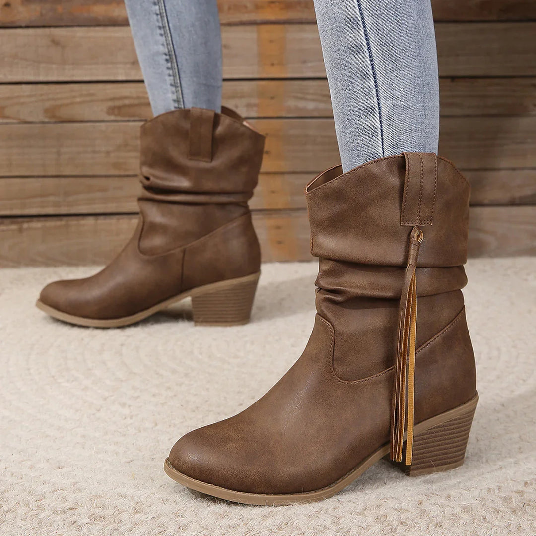 Women's brown slouchy ankle boots with tassel detail and block heel, styled with light denim jeans