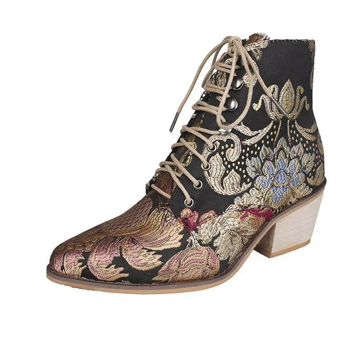 Elegant black ankle boot with floral tapestry embroidery and beige laces on a low wooden heel