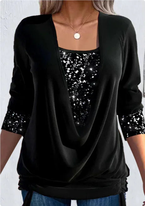Woman wearing black long sleeve top with sparkly sequin-like inner layer and gold pendant necklace