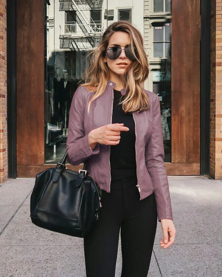 Stylish woman wearing purple leather jacket and sunglasses holding black handbag outdoors