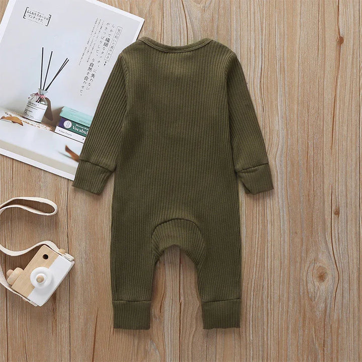 Olive green ribbed knit baby romper on wooden surface with toy camera and book