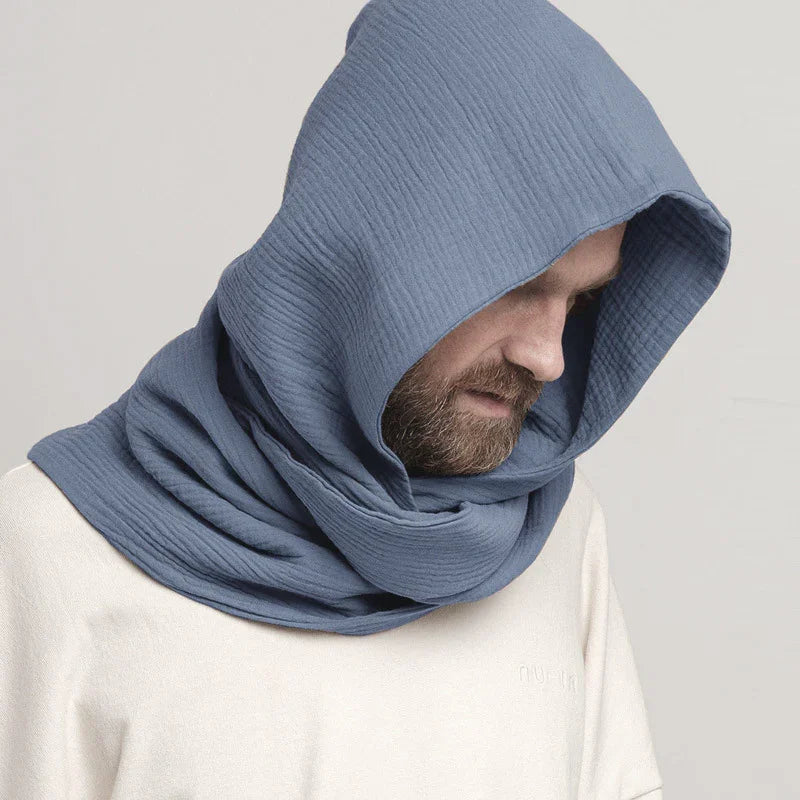 Man wearing textured blue hooded scarf with beard, neutral background, white shirt