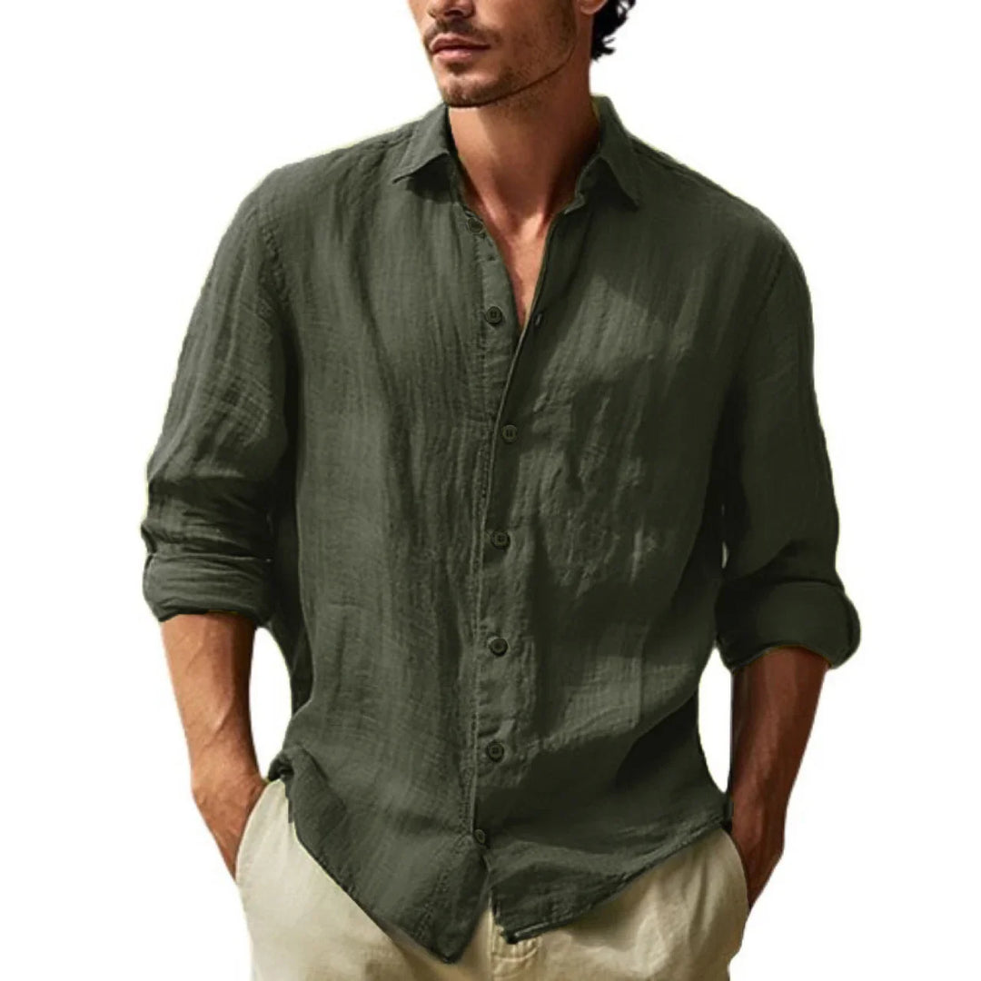 Man wearing casual dark green linen button-up shirt with rolled sleeves and beige pants