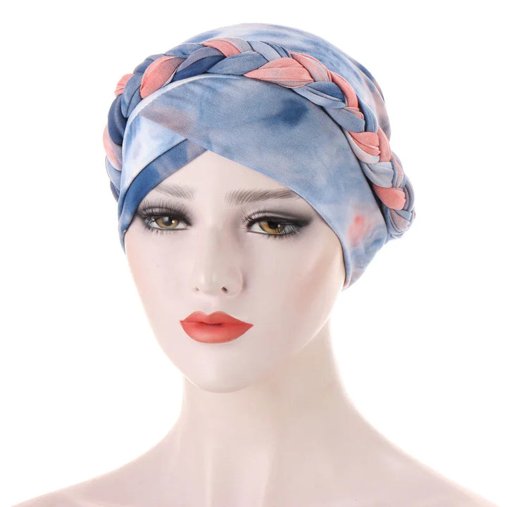Mannequin head wearing a blue and pink braided turban headwrap with soft makeup