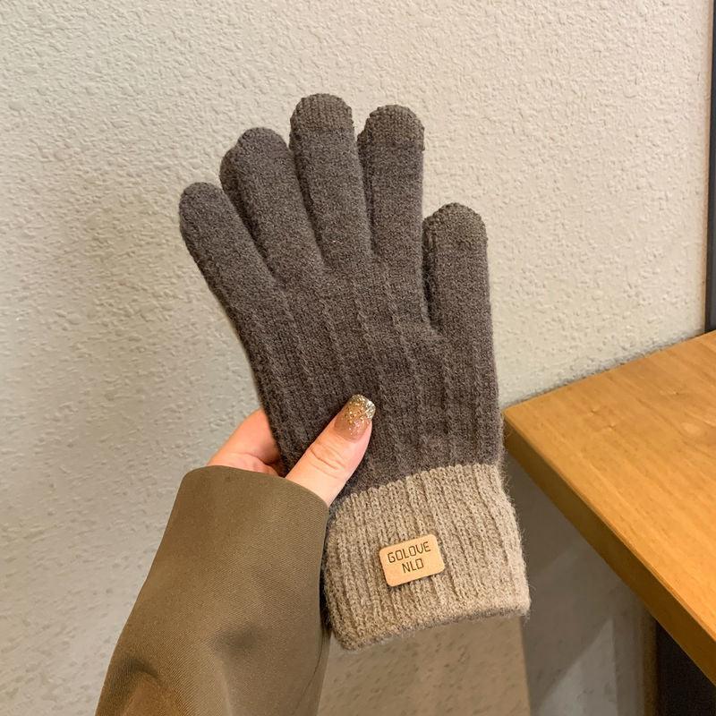 Hand holding brown knitted gloves with light beige cuffs and Golove NLD label