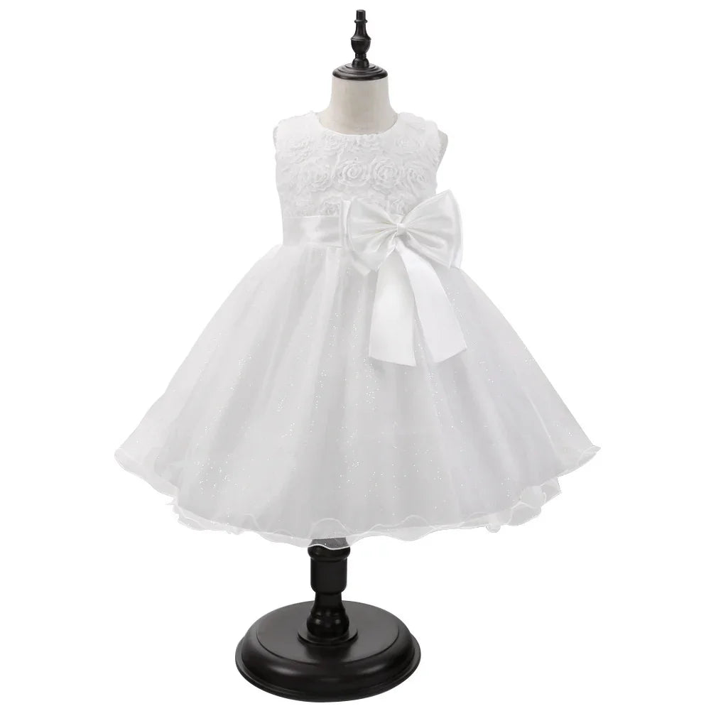 White sleeveless baby dress with floral bodice, sparkly tulle skirt, and large bow on waist