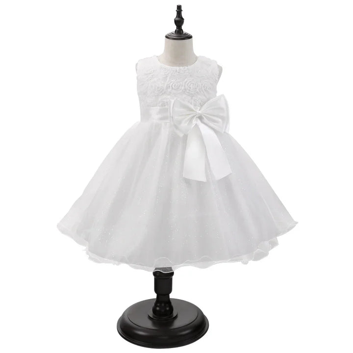 White sleeveless baby dress with floral bodice, sparkly tulle skirt, and large bow on waist
