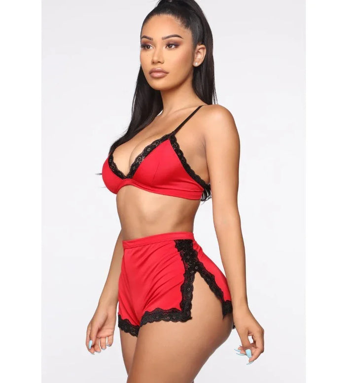 Woman modeling red bralette and shorts lingerie set with black lace trim on white background