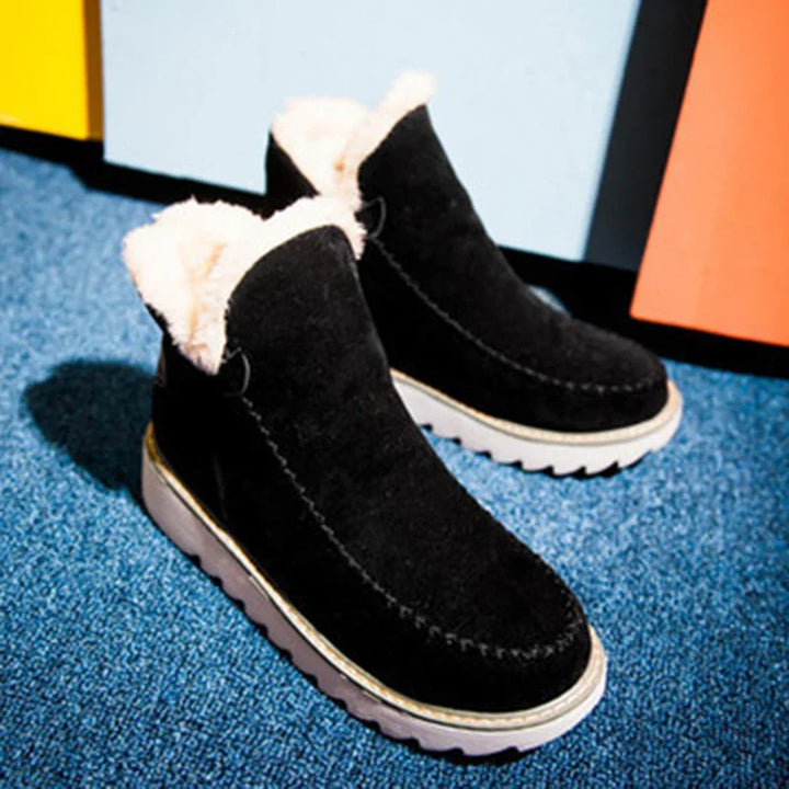 Black suede winter boots with white fur lining and white rubber soles on blue carpet