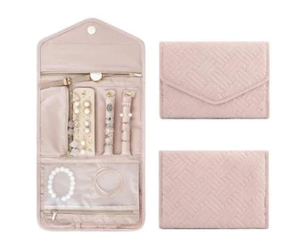 Pink quilted jewelry organizer with compartments holding pearl earrings, rings, and bracelets