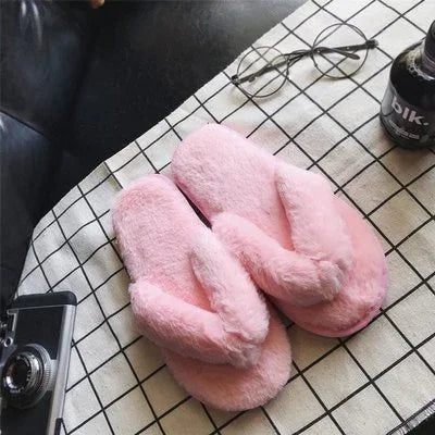 Soft pink fluffy slippers placed on a white grid-patterned cloth with vintage camera and eyeglasses nearby