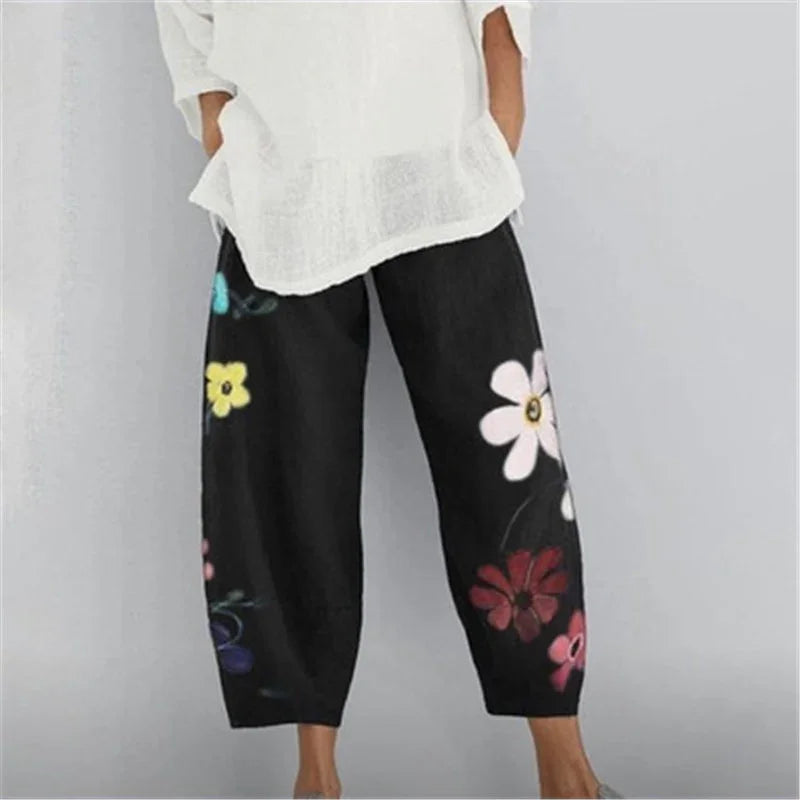 Woman wearing black wide-leg pants with colorful floral prints and a loose white top