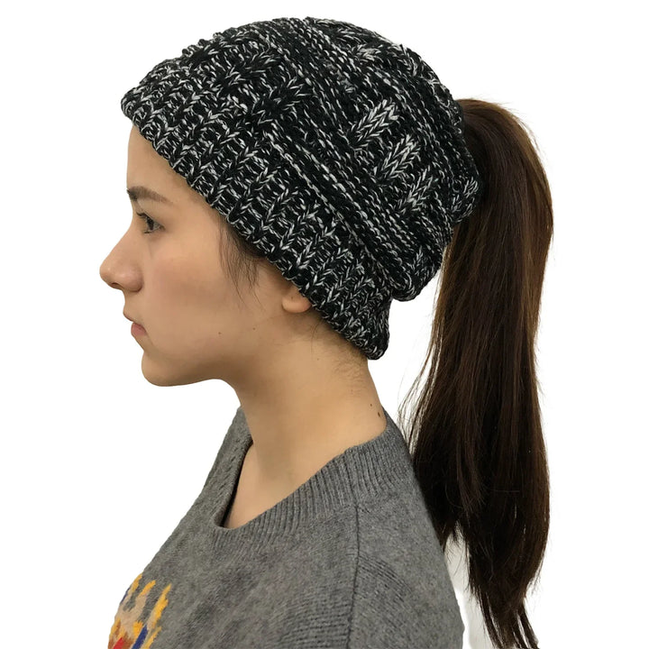 Profile of woman wearing black and white knit ponytail beanie with brown hair and grey sweater