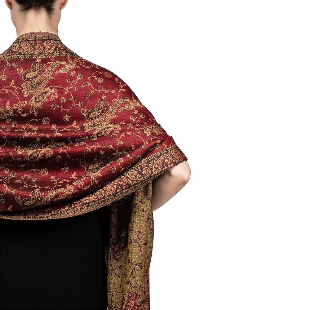Back view of person wearing red and gold paisley patterned shawl over black dress