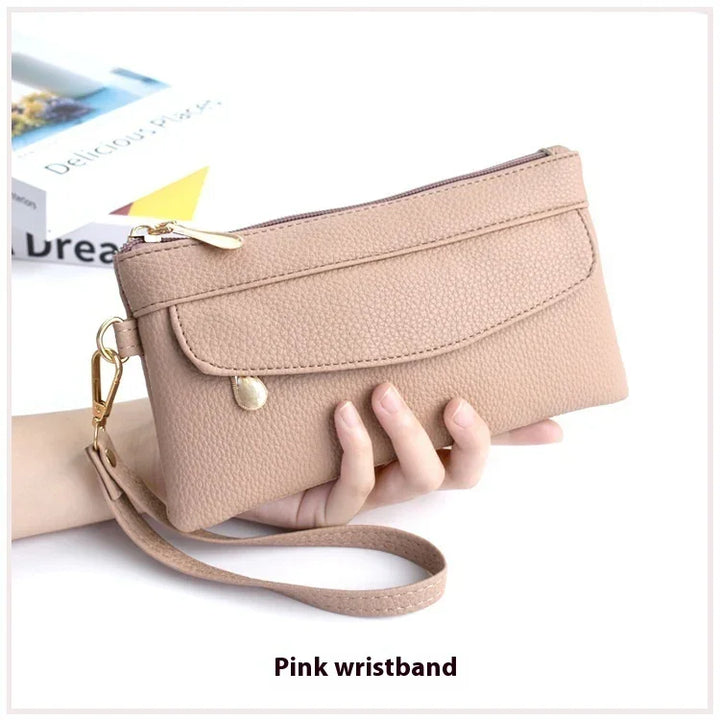 Hand holding a beige textured wristlet purse with gold zipper and clasp, on white background