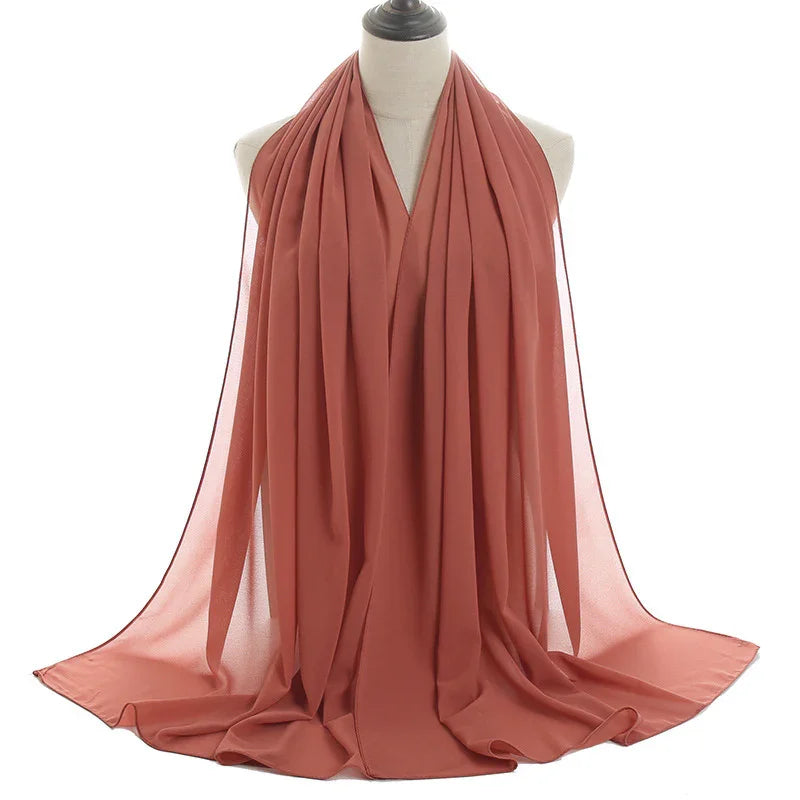 Rust-colored lightweight chiffon scarf displayed on dress form with soft draping