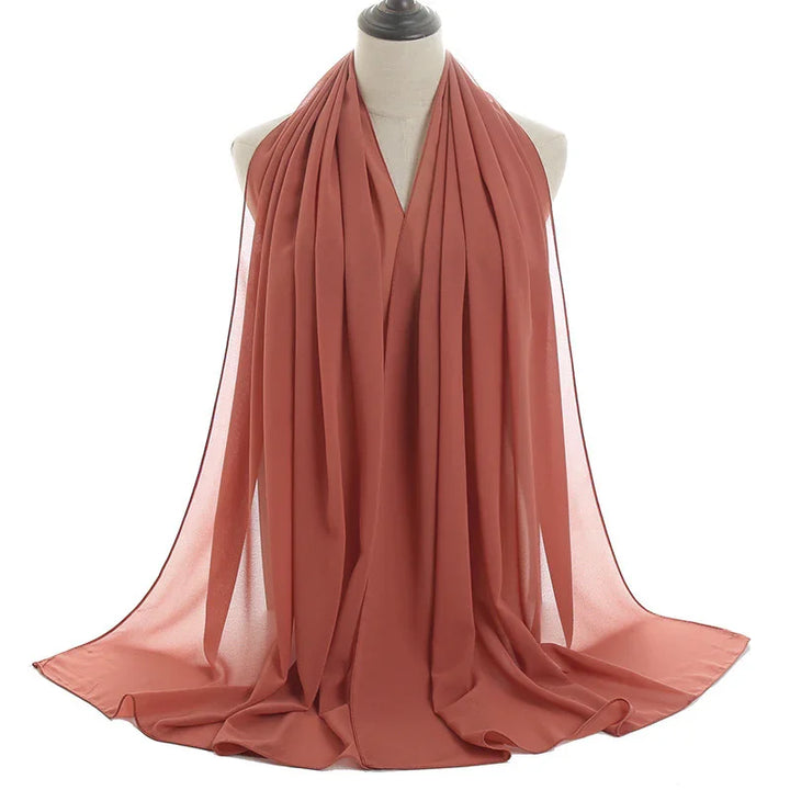 Rust-colored lightweight chiffon scarf displayed on dress form with soft draping