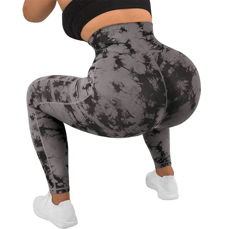 Woman wearing black and gray tie-dye high-waisted leggings squatting, paired with white sneakers