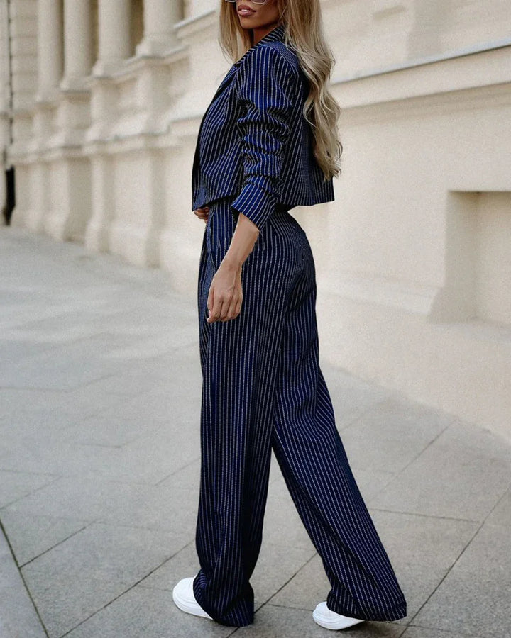 Woman in stylish navy blue pinstripe cropped blazer and wide-leg pants walking on urban street
