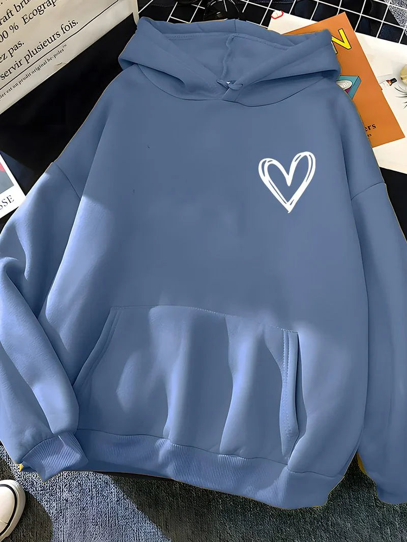 Blue hoodie with white heart design on chest, laid flat on checkered surface with books