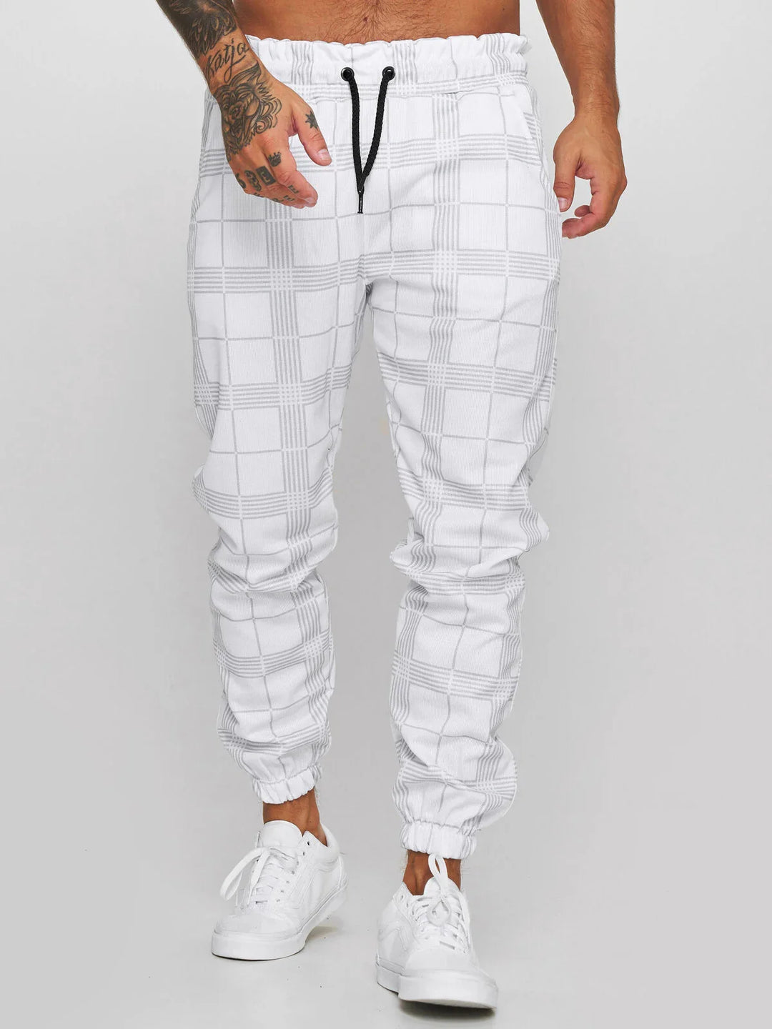 Man wearing white plaid jogger pants with black drawstring and white sneakers