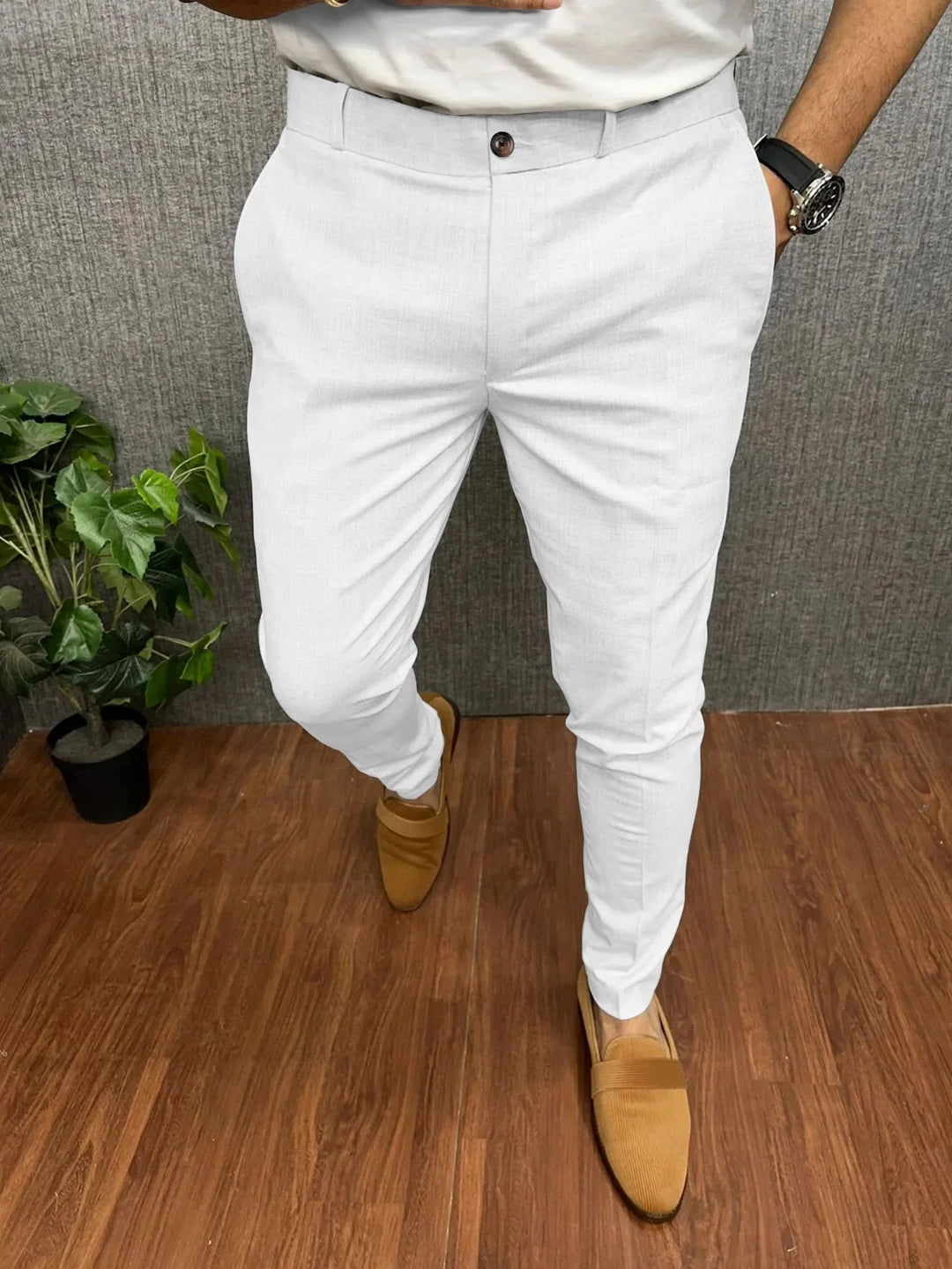 Man wearing slim fit white formal trousers and brown loafers on wooden floor