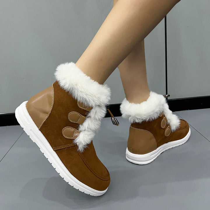 Brown winter boots with white faux fur lining and white soles worn on legs against gray floor and wall