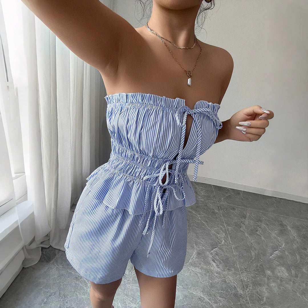 Woman wearing blue and white striped off-shoulder ruffled romper with bow details indoors