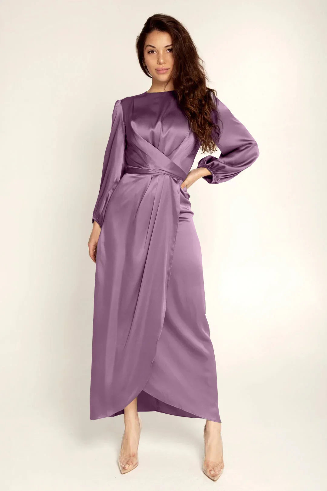 Woman in a long-sleeve purple satin wrap dress with high-low hem and clear heels