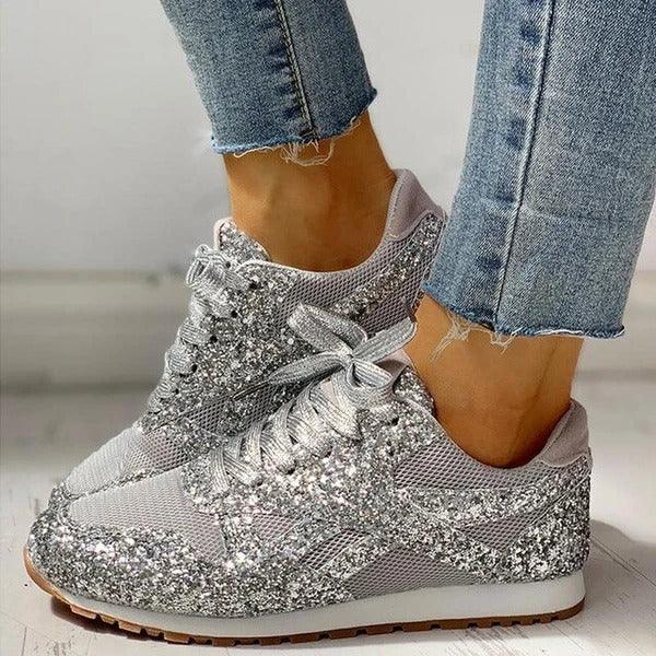 silver glitter women’s sneakers paired with frayed hem denim jeans on light background