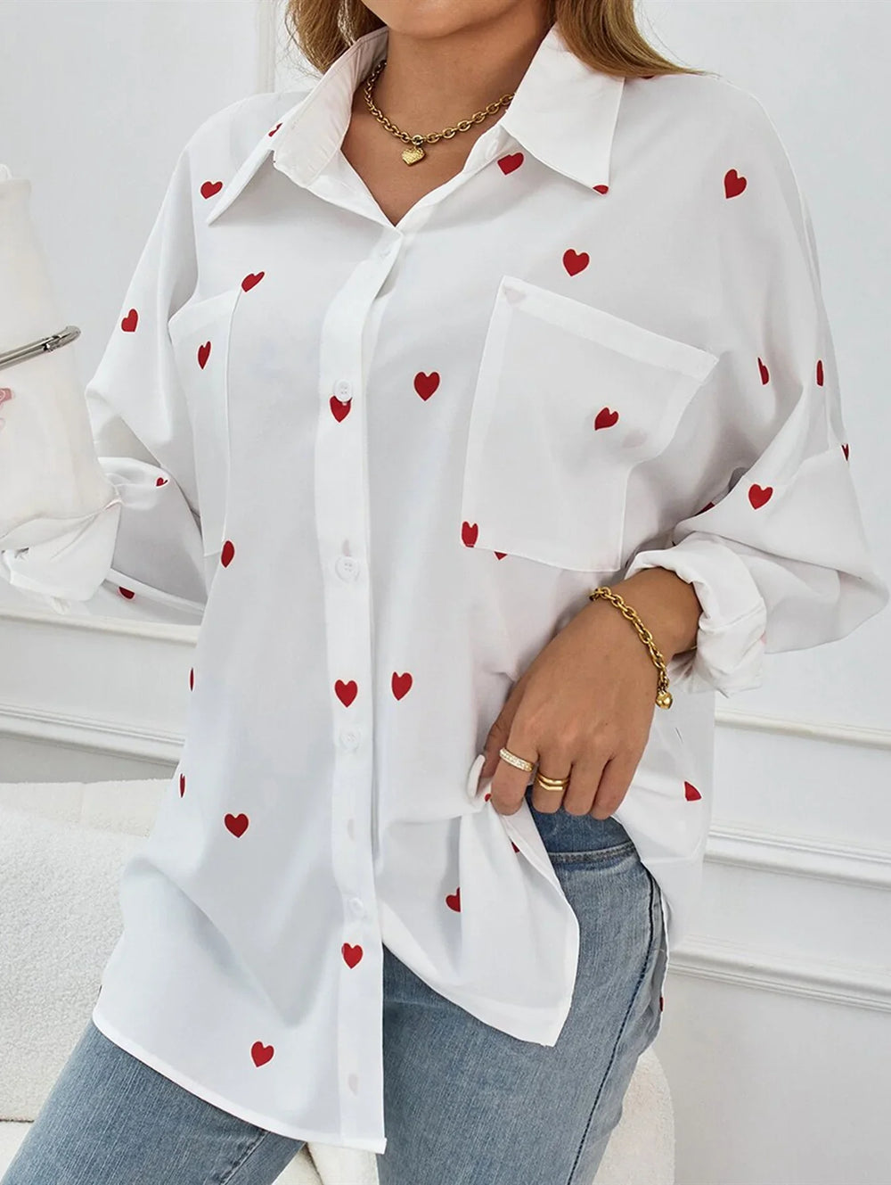 White button-up shirt with red heart prints, worn with blue jeans and gold jewelry