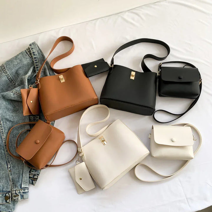 Set of stylish leather handbags in brown, black, and white with matching mini pouches on white cloth and denim