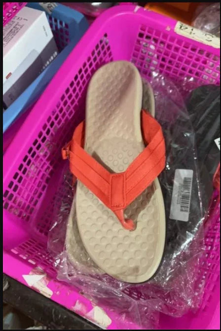 Beige sole sandal with orange straps in pink basket on store shelf