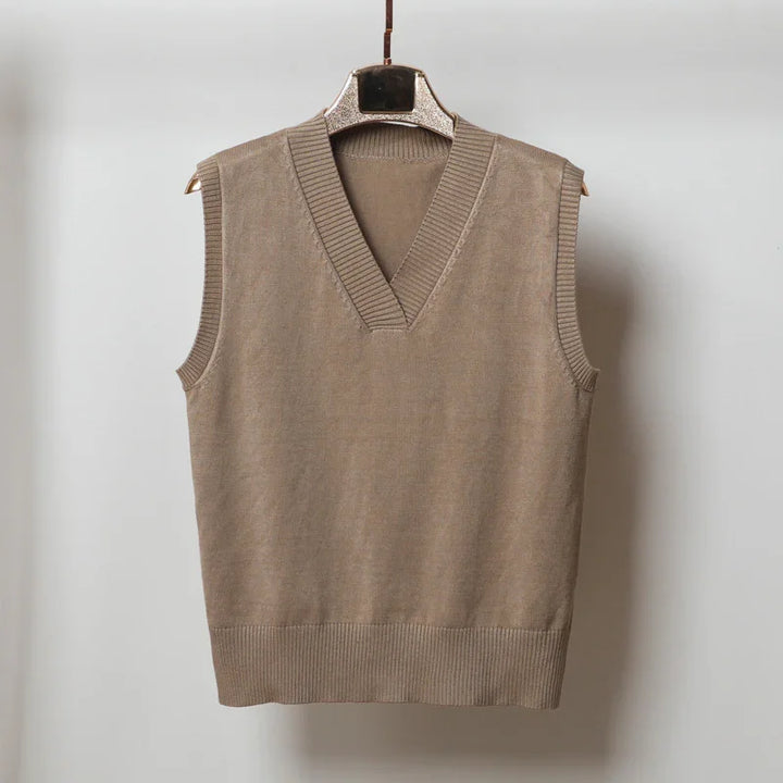 Beige knitted sleeveless V-neck sweater vest hanging on hanger against white background