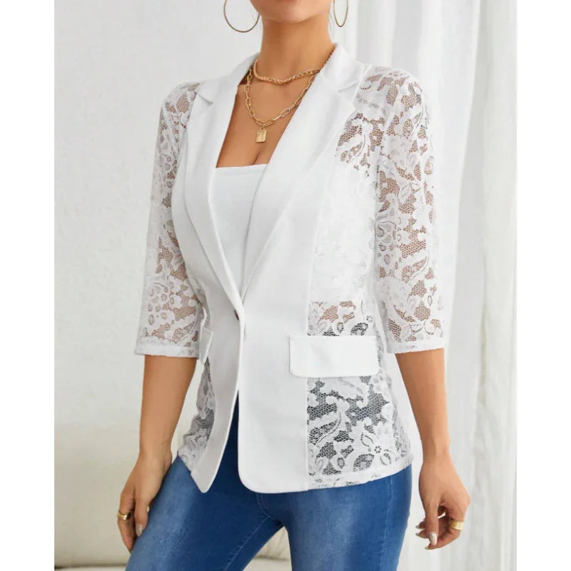 Woman wearing white lace blazer with 3/4 sleeves and blue jeans in minimal indoor setting