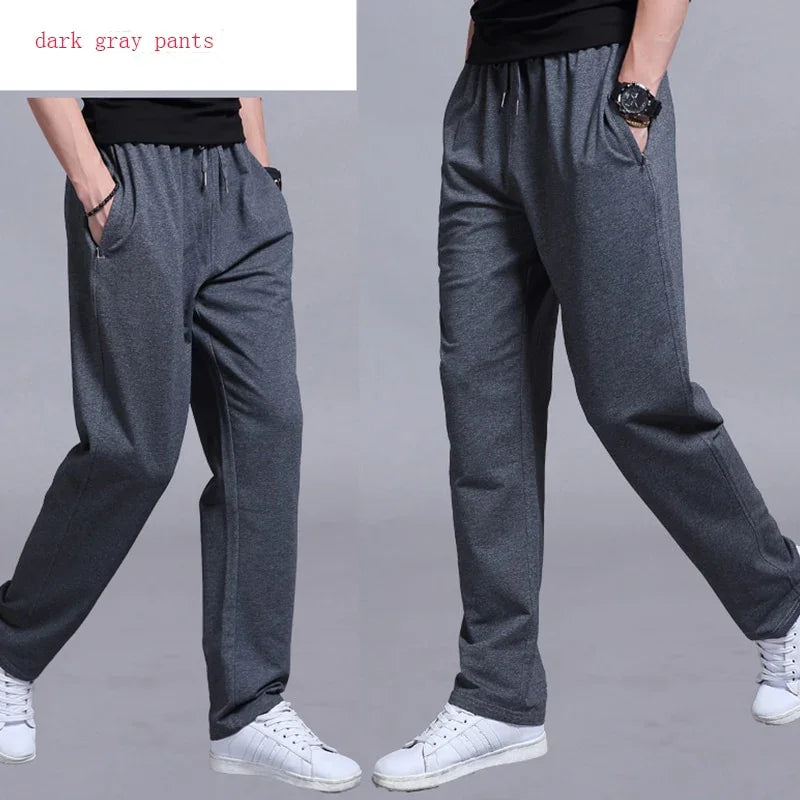 Men's dark gray casual pants with elastic waistband and pockets, paired with white sneakers