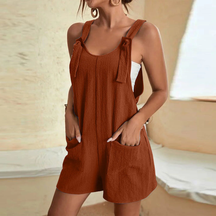 Woman wearing rust brown sleeveless romper with front pockets and tied shoulder straps