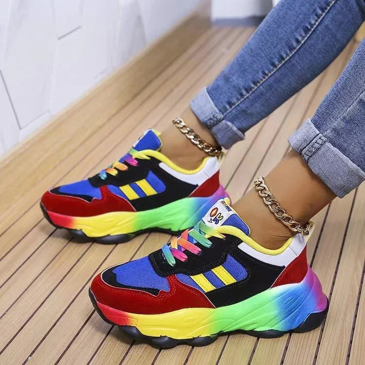 Colorful rainbow chunky sneakers with red, blue, yellow, and green accents worn with rolled-up jeans and gold ankle bracelets