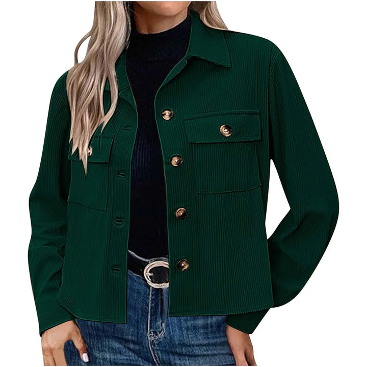 Woman wearing dark green corduroy button-up jacket with front pockets, paired with black top and blue jeans