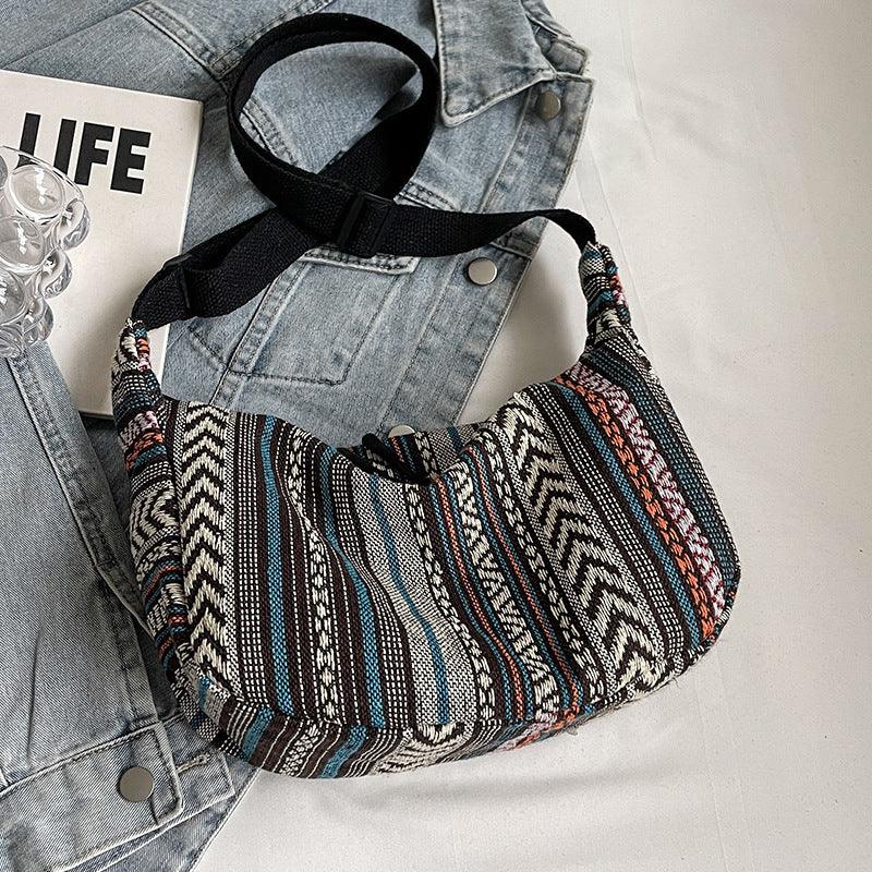 Bohemian striped fabric crossbody bag with black strap on denim jacket and LIFE book