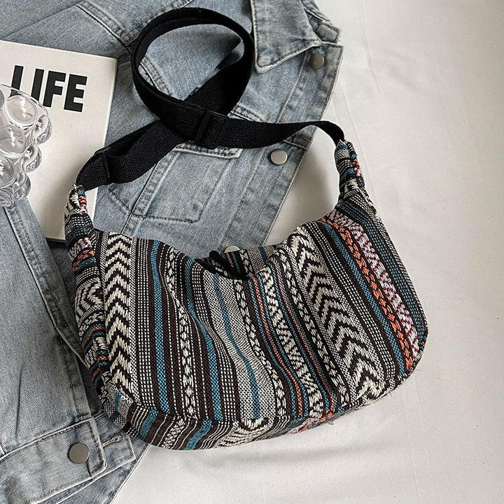 Bohemian striped fabric crossbody bag with black strap on denim jacket and LIFE book