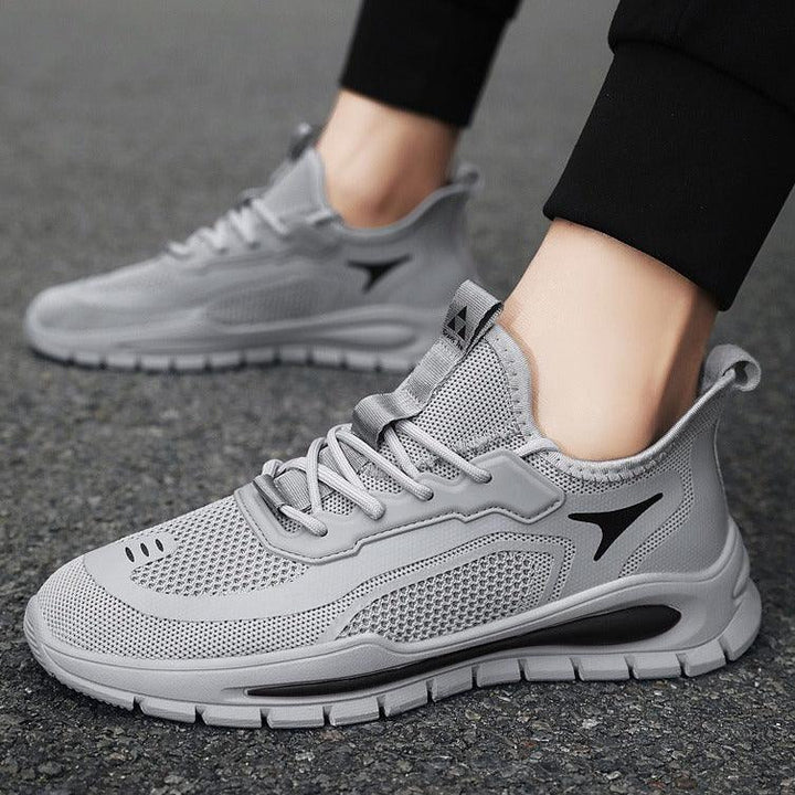 Light gray breathable mesh running shoes with black logo and flexible sole on asphalt surface