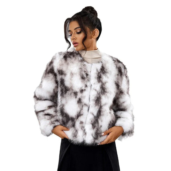 Woman wearing a white and gray spotted faux fur jacket with a high neck beige top and black skirt