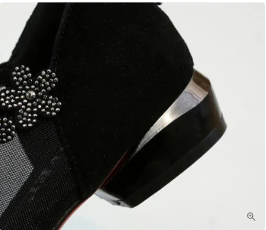 close-up of black suede women's shoe with metallic flower decoration and low heel