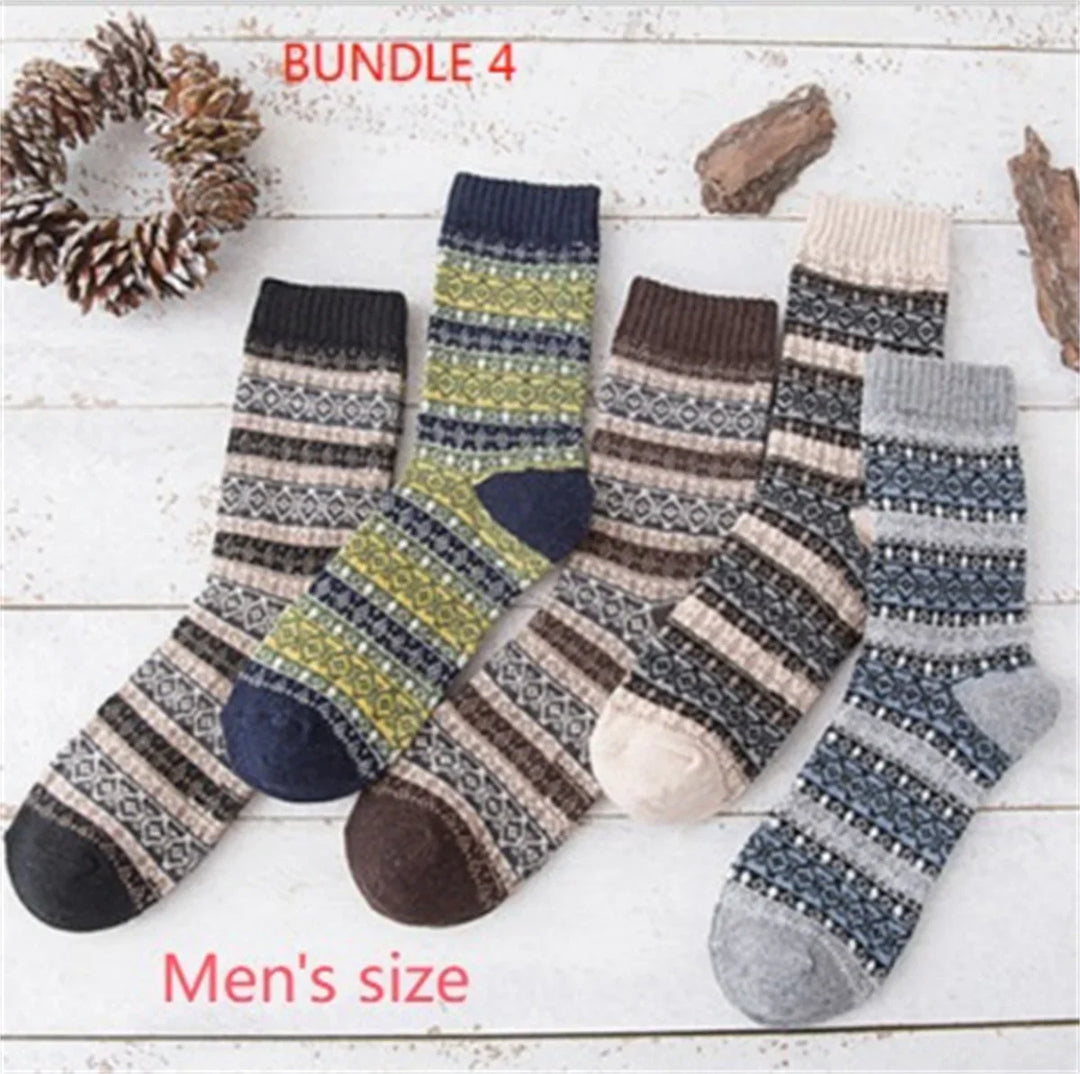 Bundle of five men's patterned wool socks in various earthy and blue tones on white wooden background