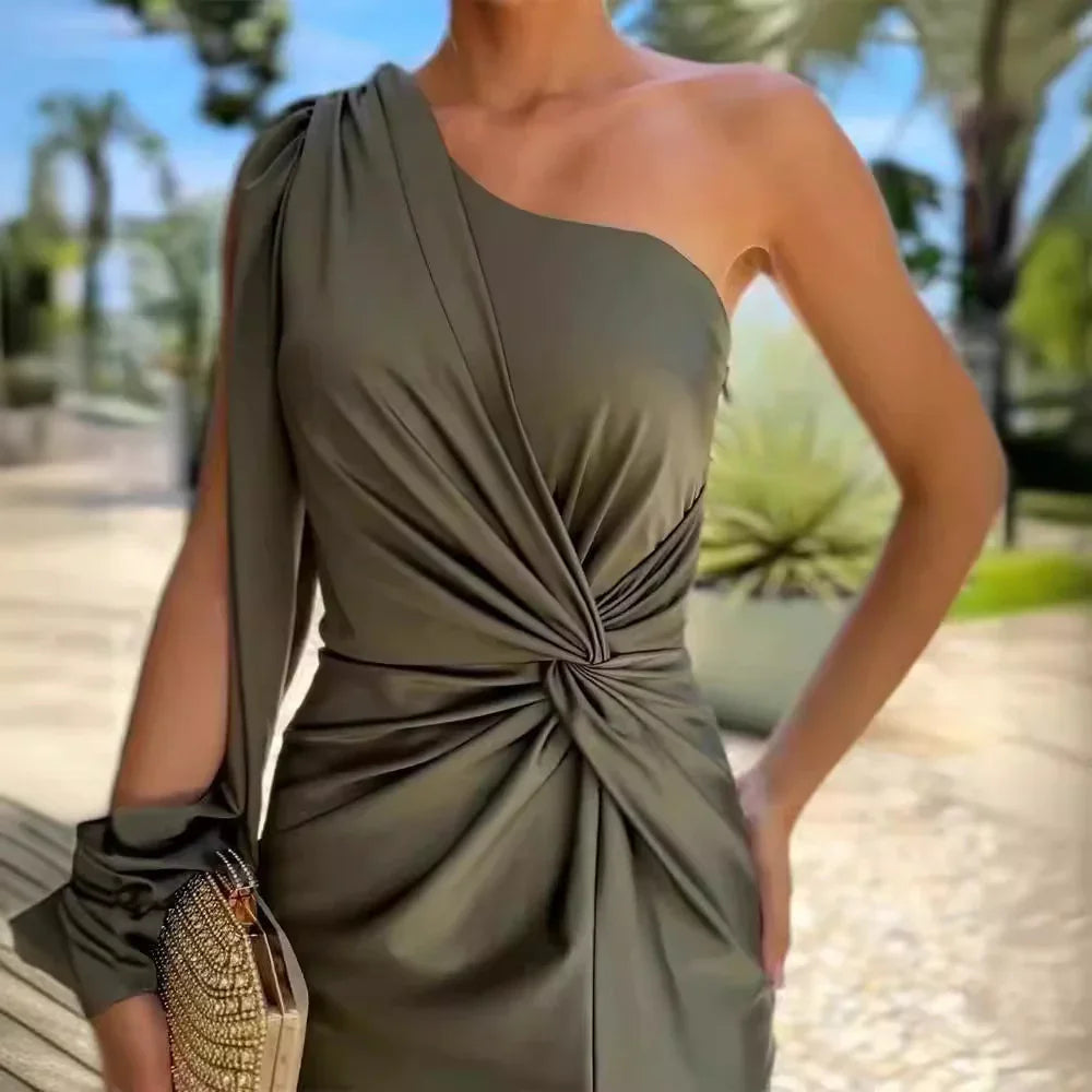 Woman in elegant olive green one-shoulder twisted detail dress holding embellished clutch outdoors